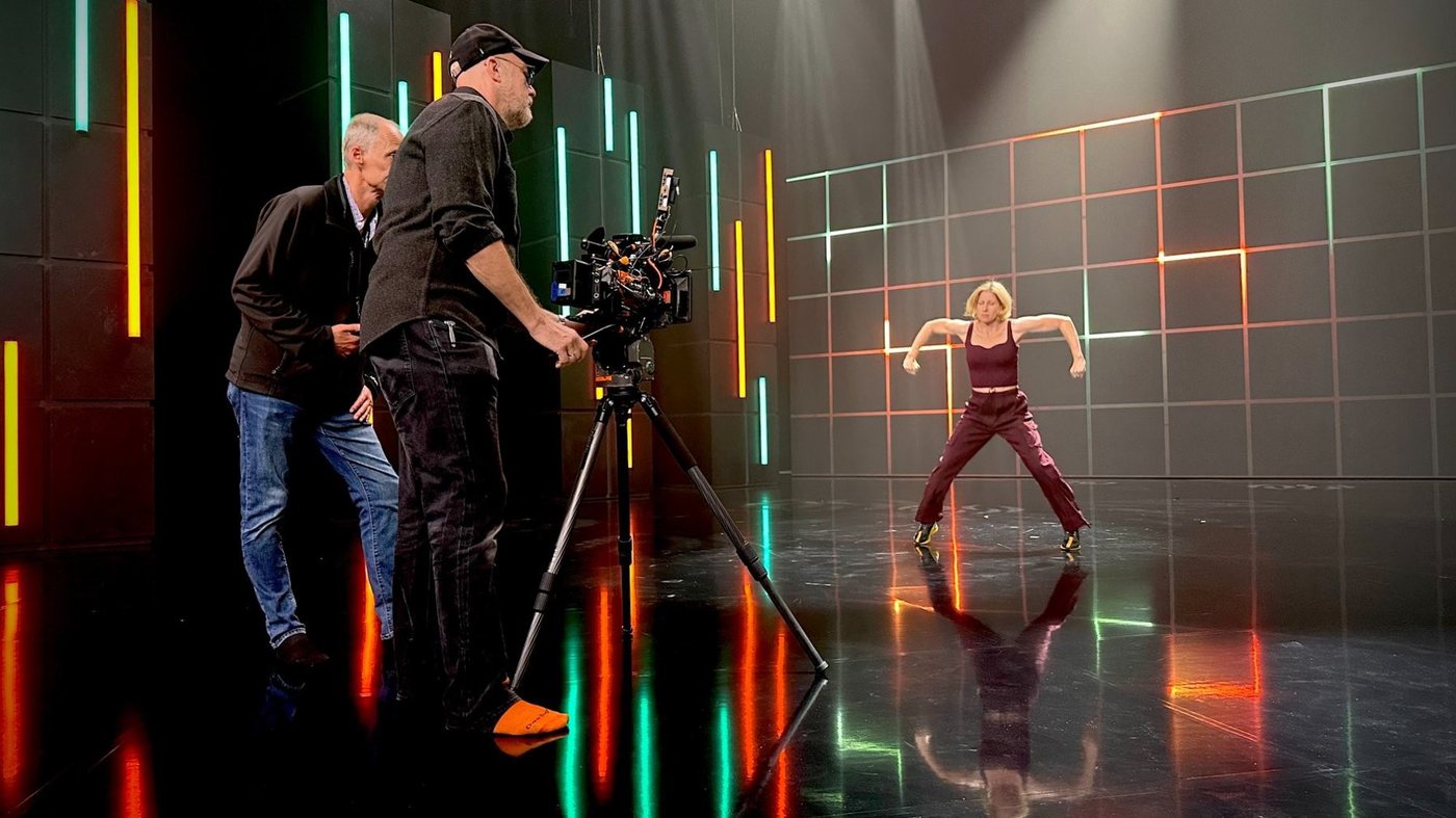Kristian Dane Lawing at camera on a lit stage during a take